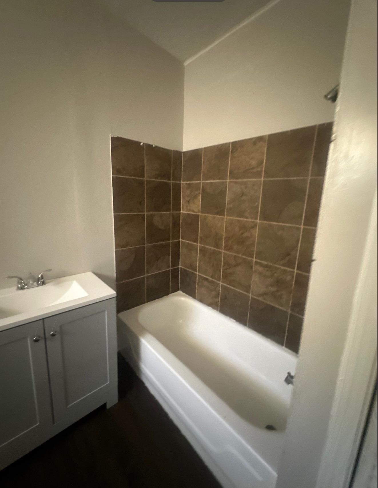 1165 Rayner Street Memphis, TN 38106 - Photo 12 of 16 Full bathroom with a white tub-shower combination, brown wall tiling, and a gray vanity cabinet with an integrated sink