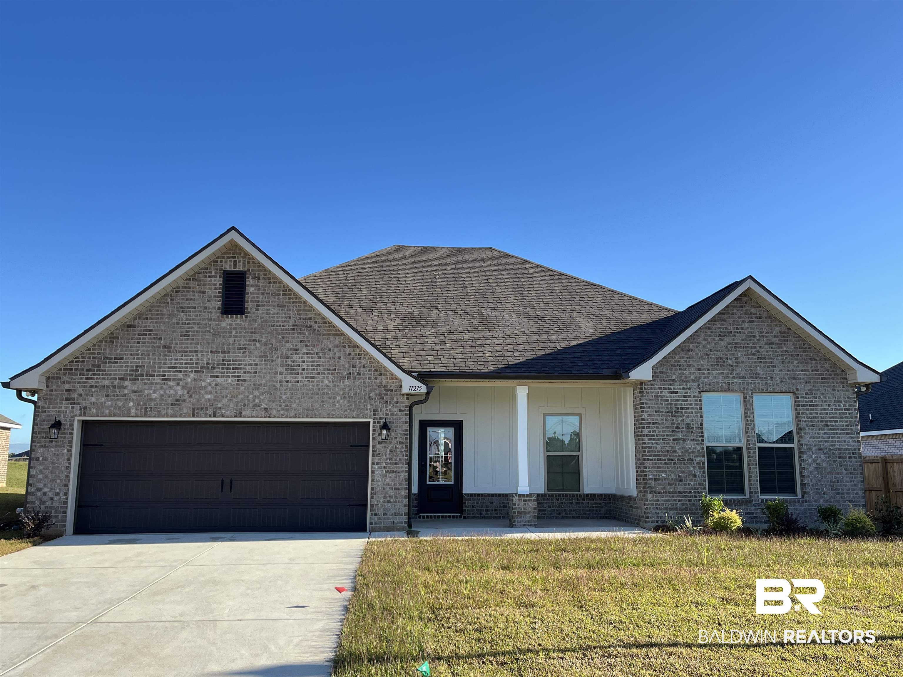 11275 Bonaventure Avenue Daphne, AL 36526 - Photo 1 of 3 View of front facade with covered porch, a front lawn, an attached garage, driveway, and board and batten siding