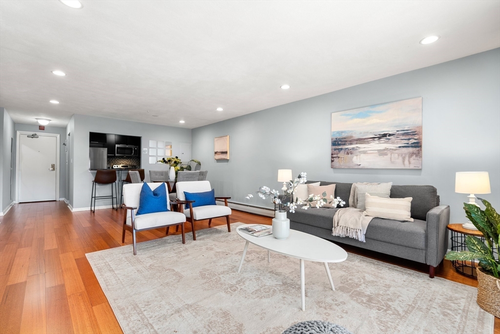 32 Whites Avenue, Unit E441 Watertown, MA 02472 - Photo 4 of 34 a living room with furniture kitchen view and a wooden floor