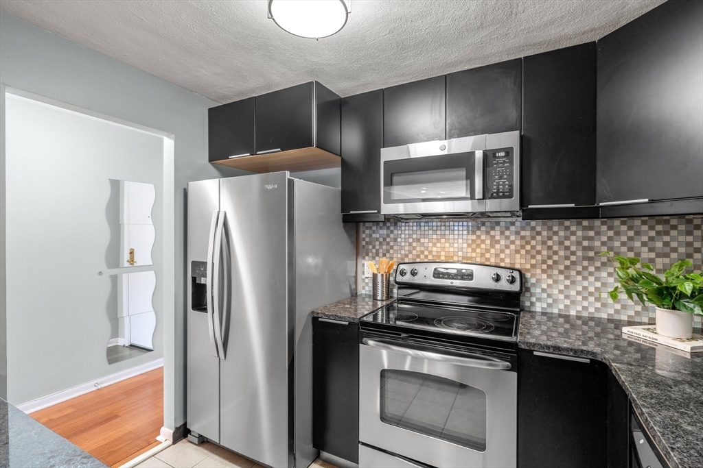 32 Whites Avenue, Unit E441 Watertown, MA 02472 - Photo 10 of 34 a kitchen with granite countertop a refrigerator stove and microwave