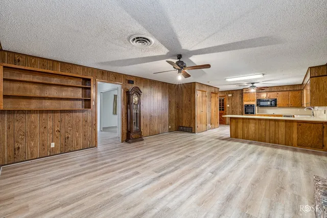 an empty room with wooden floor fireplace and windows