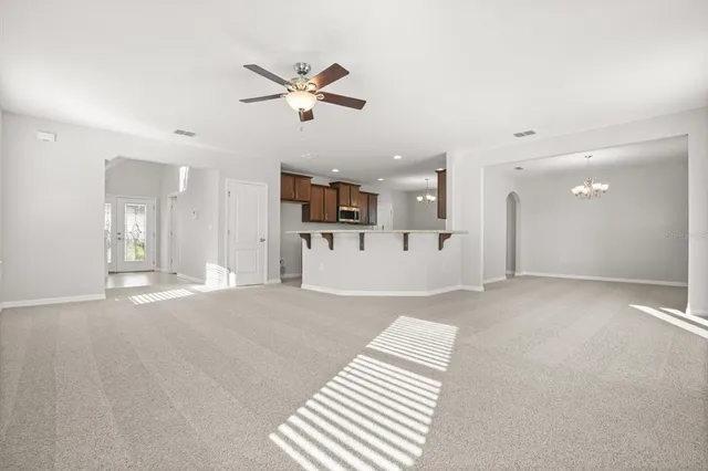 a view of a living room a kitchen and a chandelier fan