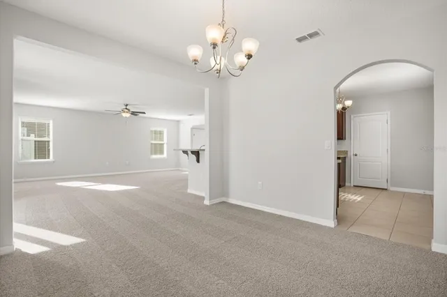 a view of a livingroom with a chandelier fan and windows