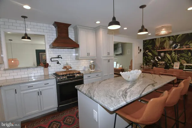 a kitchen with stainless steel appliances granite countertop a stove a sink a refrigerator a center island a dining table and chairs