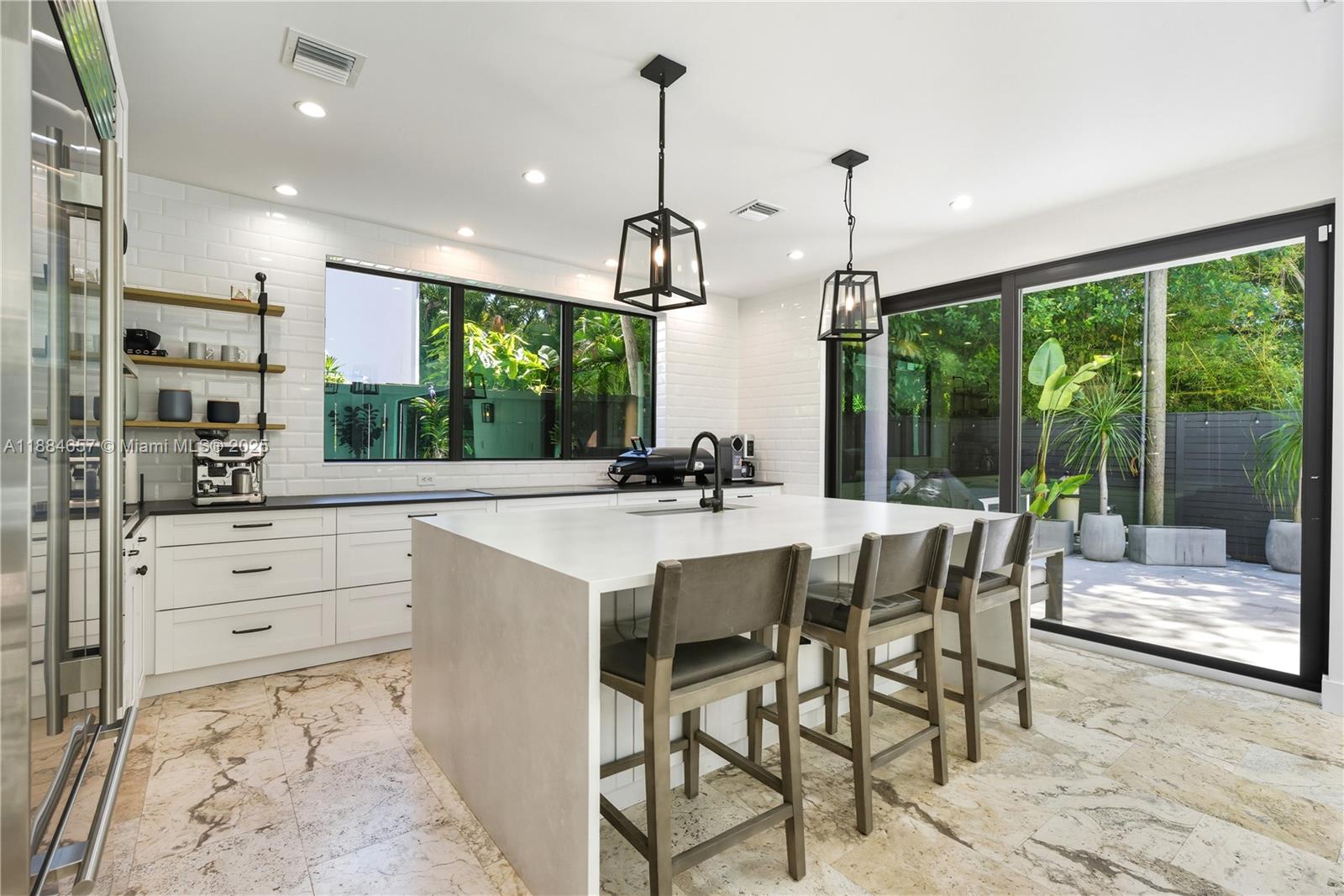 3782 El Prado Boulevard, Unit 1 Miami, FL 33133 - Photo 5 of 30 a kitchen with kitchen island a counter top space appliances and a dining table