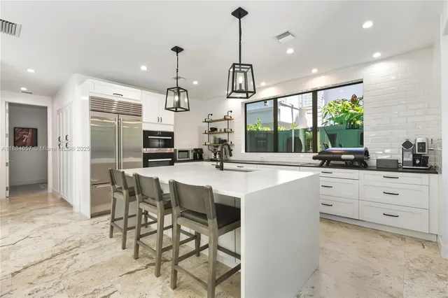 a kitchen with stainless steel appliances kitchen island a table and chairs in it
