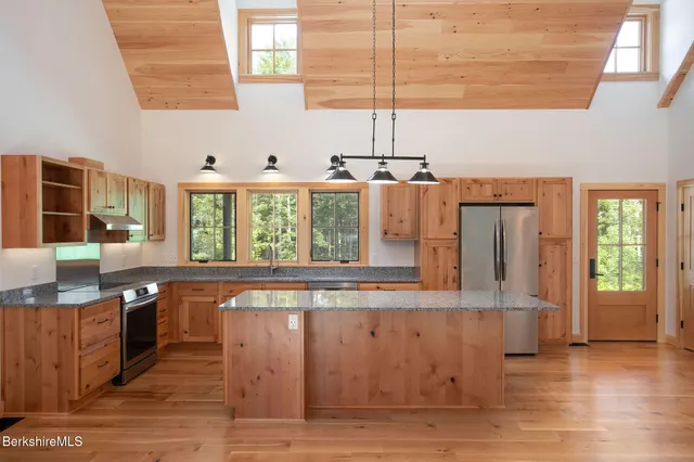 a large kitchen with stainless steel appliances granite countertop a stove a sink and a wooden floors