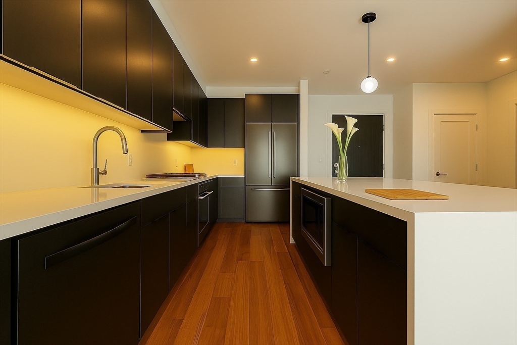 99 Sumner Street, Unit 606 Boston, MA 02128 - Photo 3 of 22 a large kitchen with granite countertop a sink and cabinets