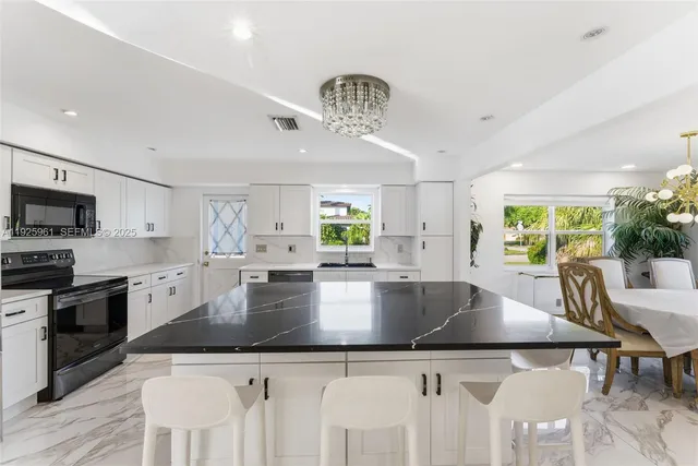 a large kitchen with stainless steel appliances a large center island attached withe living room