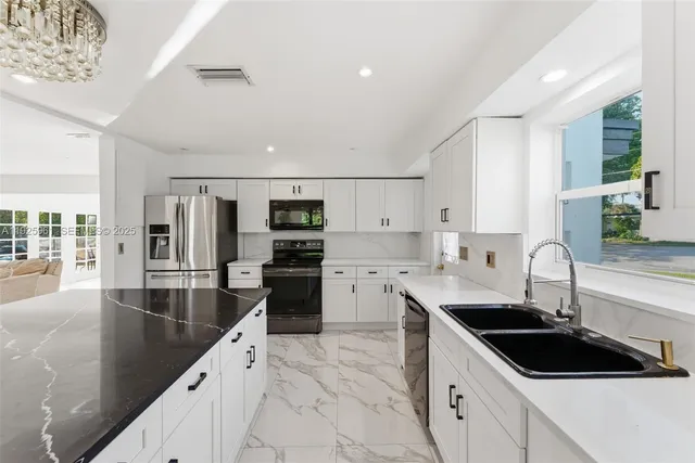 a kitchen with stainless steel appliances kitchen island granite countertop a sink a stove and cabinets