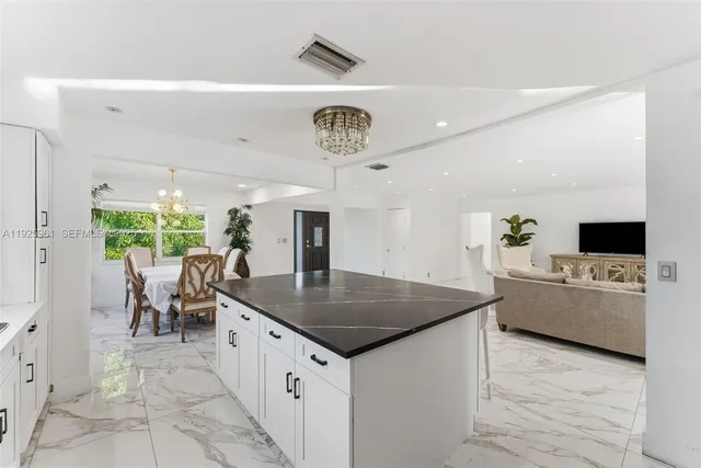 a kitchen with a stove a refrigerator and a living room view