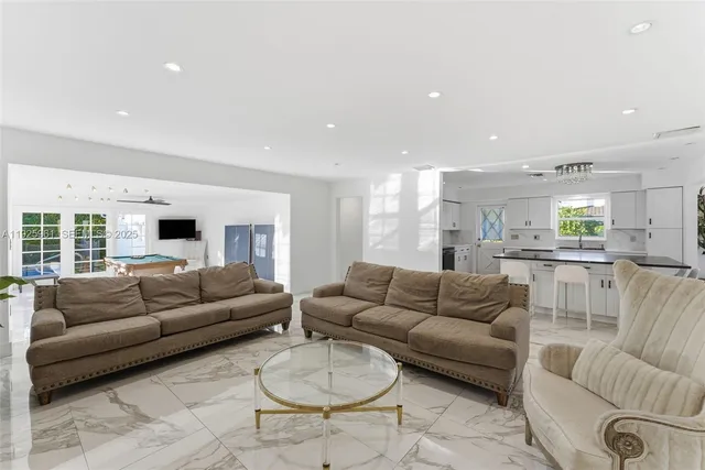 a living room with furniture white walls and kitchen view