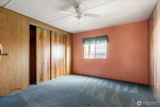 an empty room with chandelier fan and windows