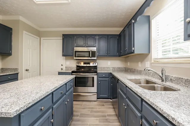 a kitchen with kitchen island granite countertop a sink a counter top space appliances and cabinets