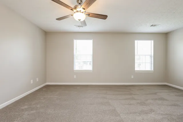 an empty room with a window and a fan