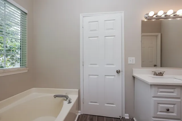 a bathroom with a tub a sink and a window
