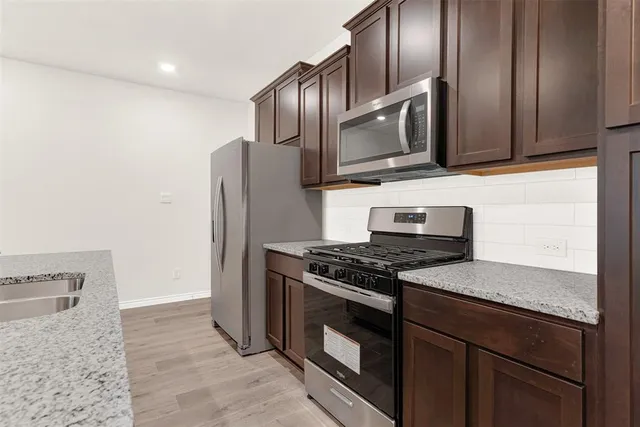 a kitchen with stainless steel appliances granite countertop a stove microwave and refrigerator