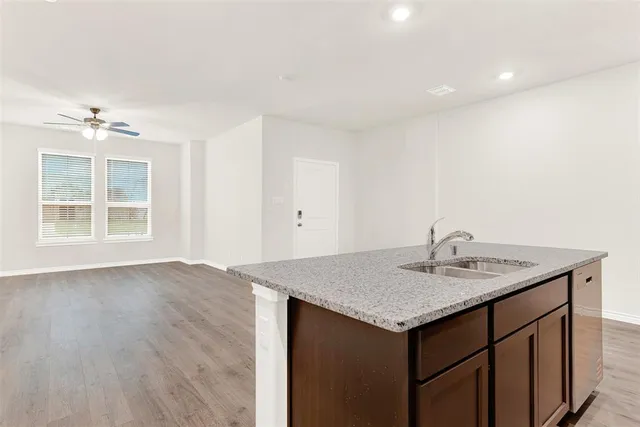an empty room with wooden floor ceiling fan and windows