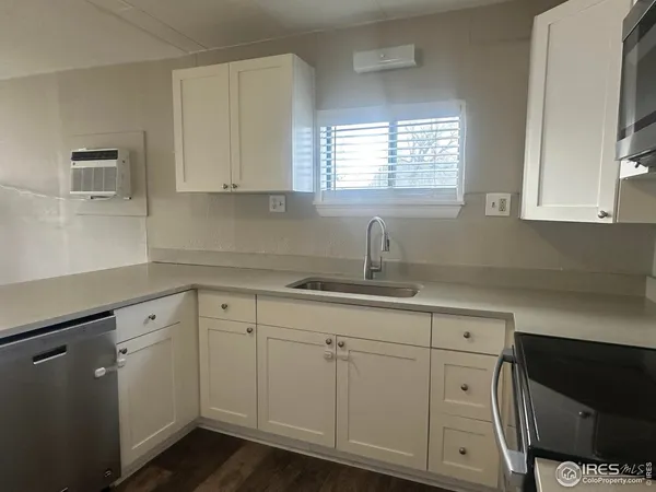 a kitchen with white cabinets white appliances sink and dishwasher with wooden floor