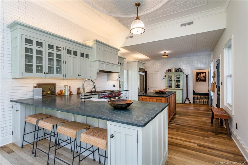 49 Christian Street Washington, CT 06777 - Photo 7 of 40 a kitchen with granite countertop a stove a sink a dining table and chairs with wooden floor