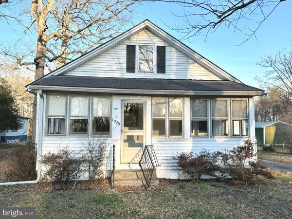 a view of a house with a yard and lawn chairs under an umbrella