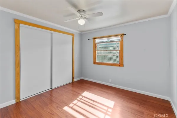 an empty room with wooden floor chandelier fan and windows