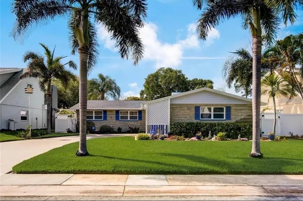 a front view of a house with a garden and palm trees