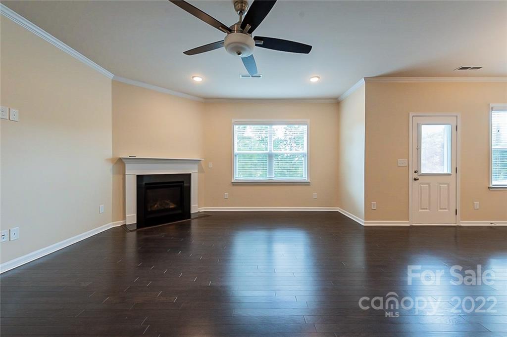 210 Keating Pl Drive Fort Mill, SC 29708 - Photo 4 of 20 an empty room with wooden floor a ceiling fan and a fireplace