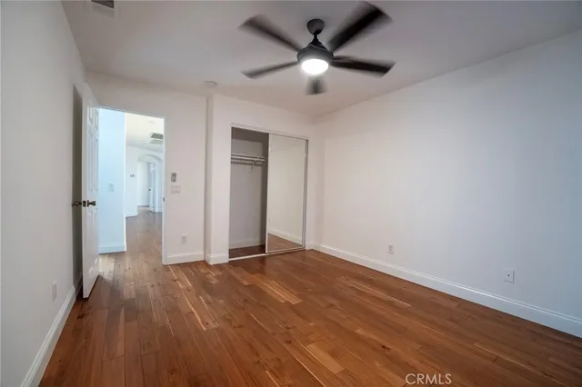 an empty room with wooden floor and a ceiling fan