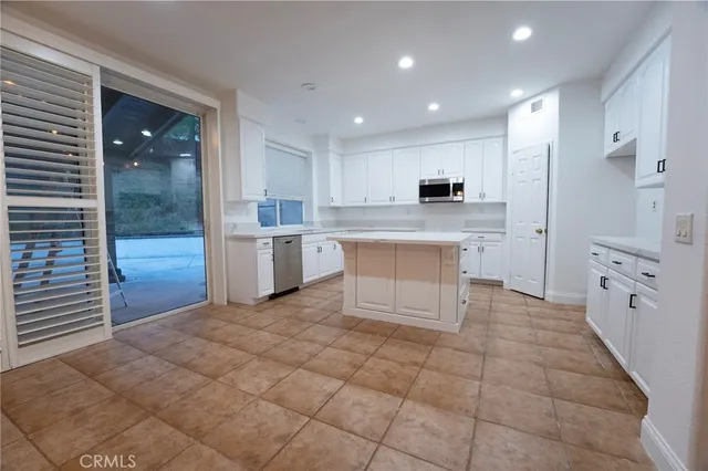a large white kitchen with stainless steel appliances granite countertop a sink and cabinets