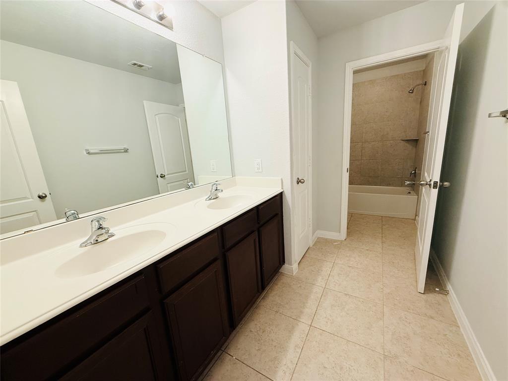 223 Magnolia Drive Princeton, TX 75407 - Photo 20 of 29 a bathroom with a double vanity sink a mirror and a bathtub