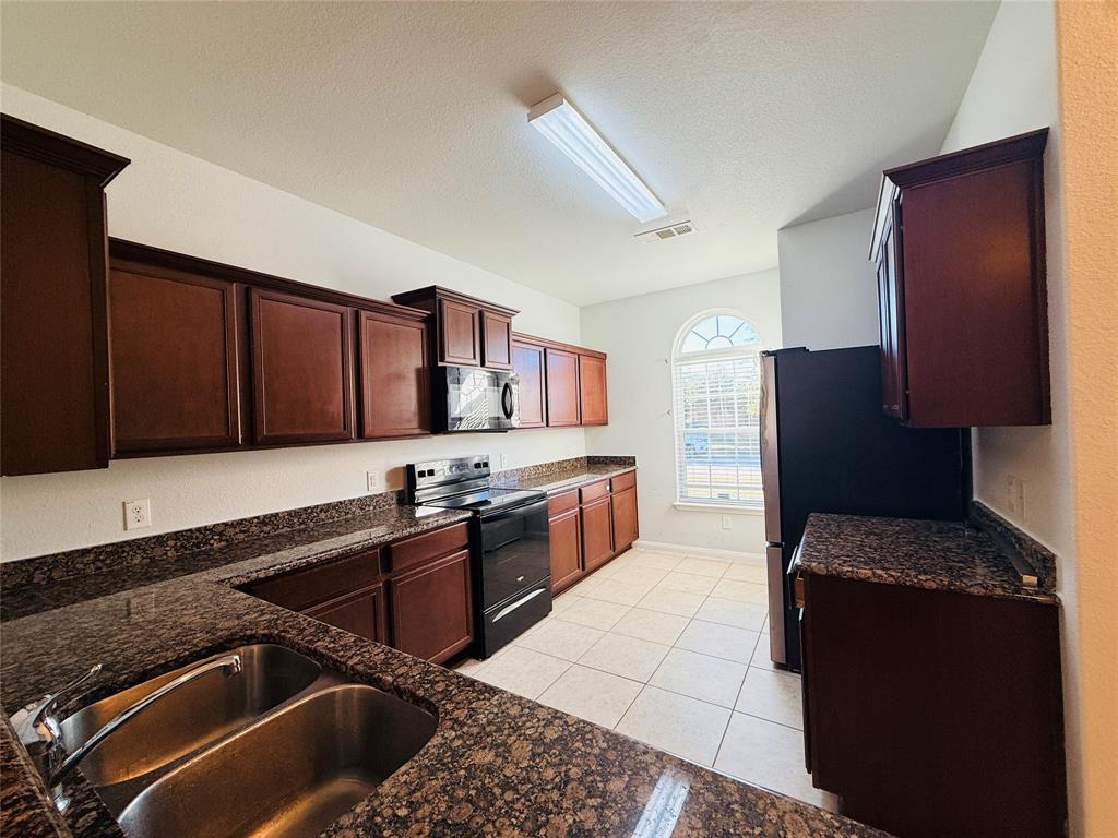 223 Magnolia Drive Princeton, TX 75407 - Photo 5 of 29 a kitchen with stainless steel appliances granite countertop a sink stove and refrigerator