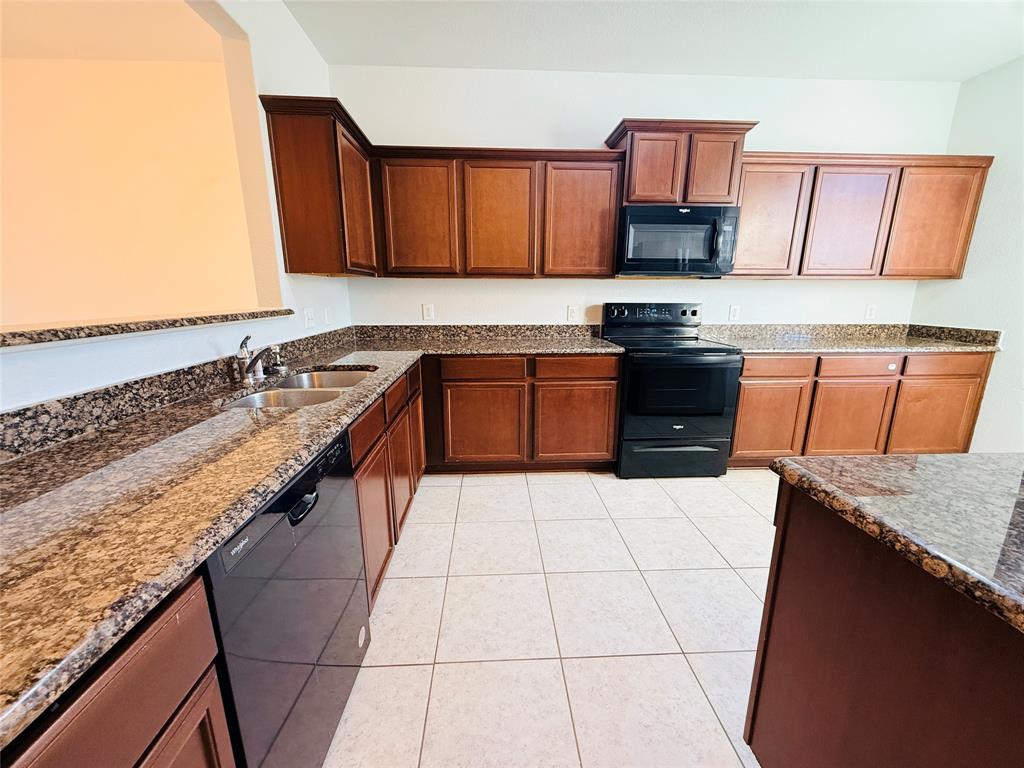 223 Magnolia Drive Princeton, TX 75407 - Photo 6 of 29 a kitchen with granite countertop a sink a stove top oven and cabinetry