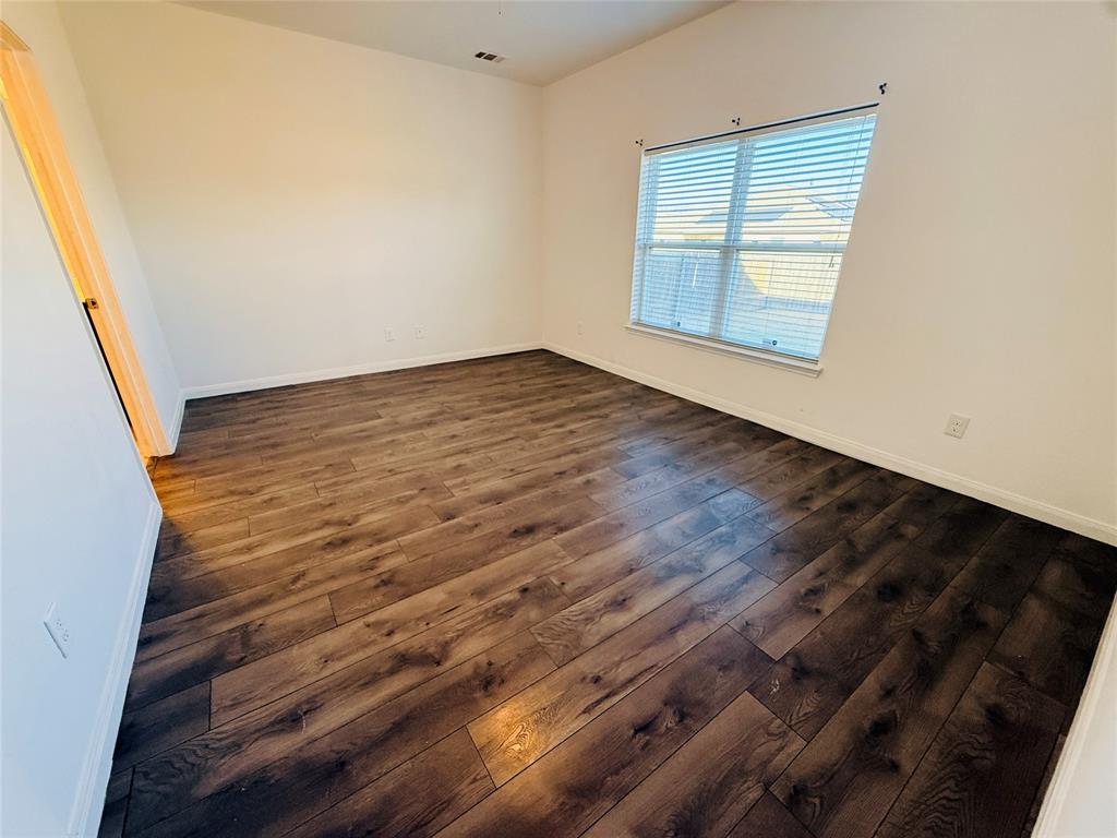 223 Magnolia Drive Princeton, TX 75407 - Photo 9 of 29 an empty room with wooden floor and windows