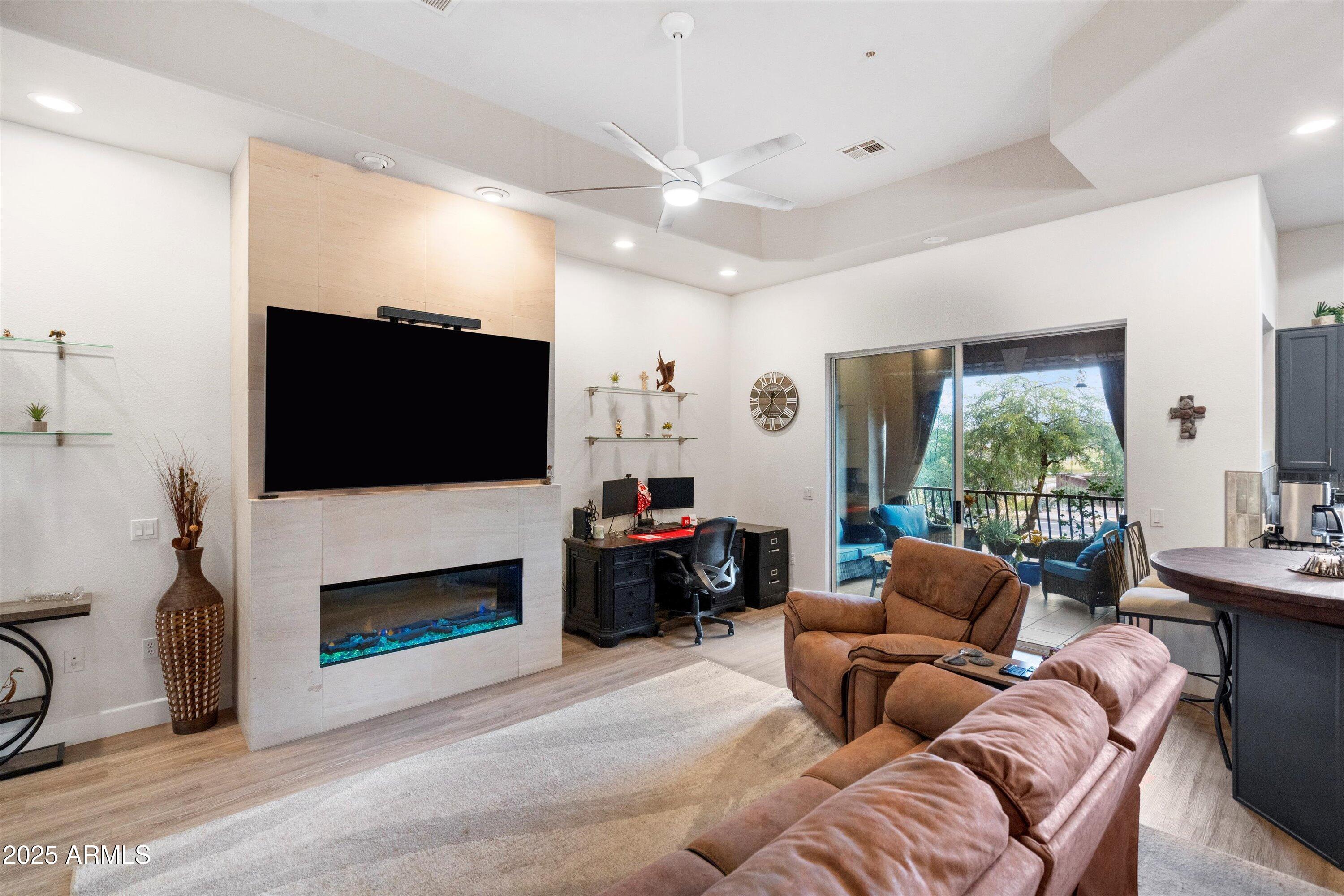 8245 East Bell Road, Unit 250 Scottsdale, AZ 85260 - Photo 10 of 48 a living room with furniture a flat screen tv and a fireplace
