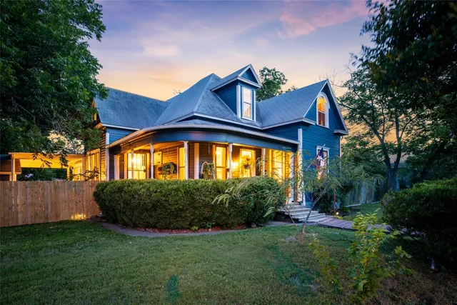a view of a house with a small yard and a large tree