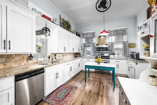 a kitchen with kitchen island granite countertop a sink cabinets and stainless steel appliances