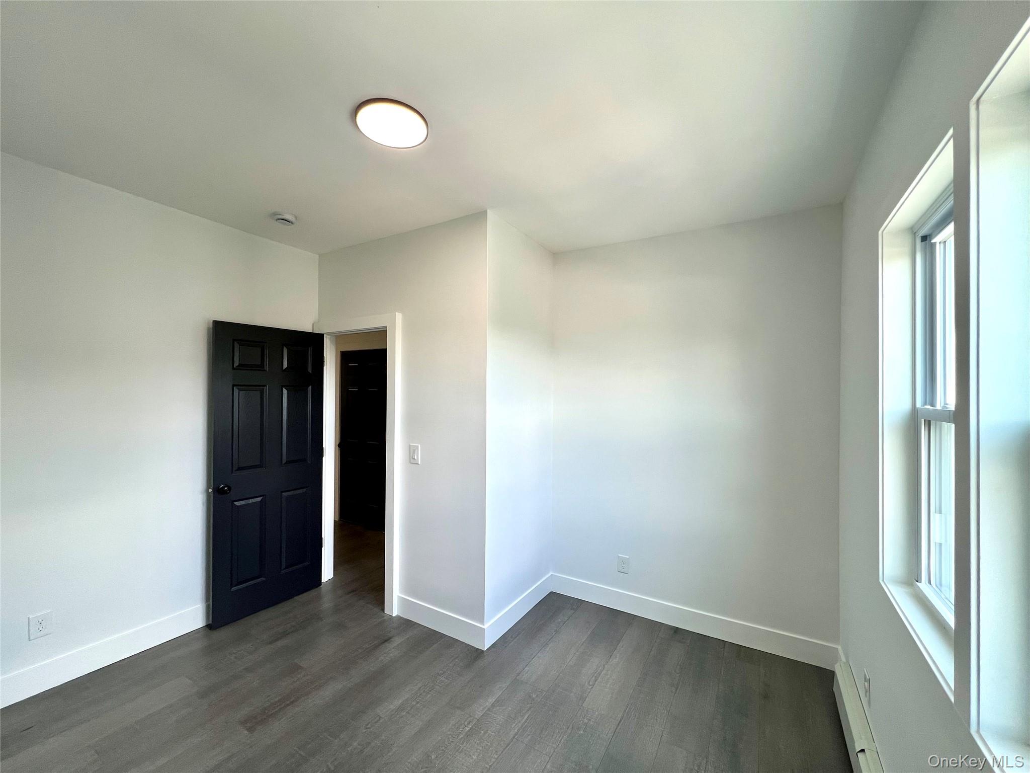79 Orchard Street, Unit 2 Yonkers, NY 10703 - Photo 20 of 26 an empty room with wooden floor and windows