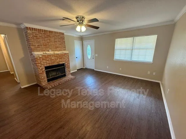 an empty room with wooden floor fireplace and windows