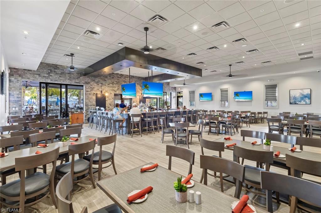 19902 Beverly Park Road Estero, FL 33928 - Photo 46 of 47 Dining space featuring a ceiling fan, a high ceiling, a drop ceiling, wood finished floors, and plenty of natural light
