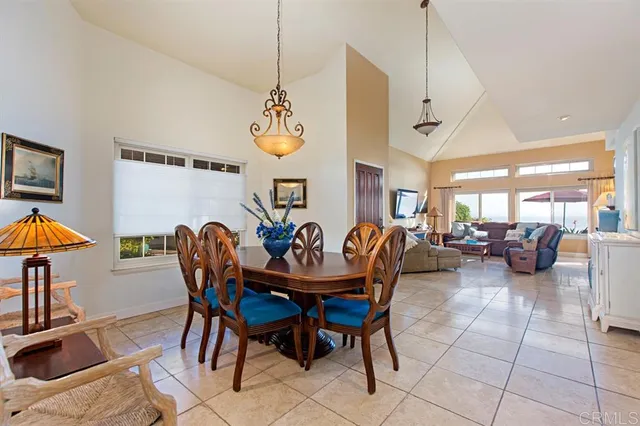 a view of a dining room and livingroom with furniture wooden floor a rug a painting and a chandelier