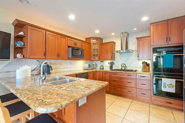 a kitchen with kitchen island granite countertop a stove top oven a sink dishwasher and cabinets with wooden floor