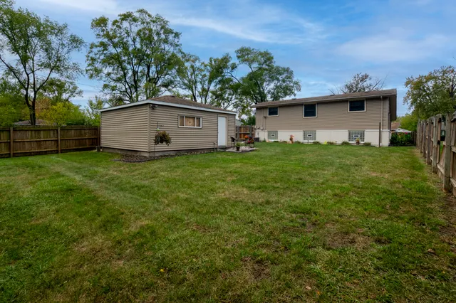 a backyard of a house with plants and large tree