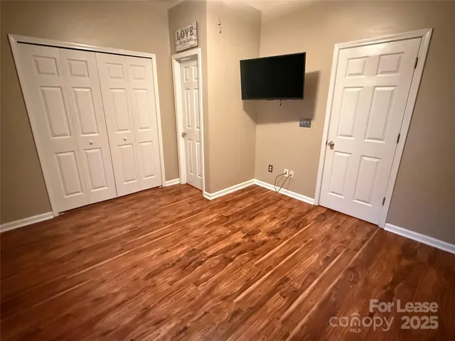 an empty room with wooden floor and bathroom