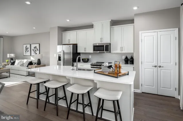 a kitchen with stainless steel appliances granite countertop a stove a refrigerator a sink a dining table and chairs with wooden floor