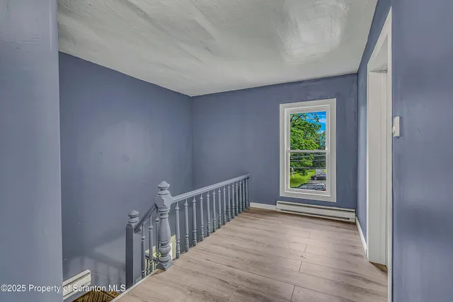 a view of an empty room with wooden floor and closet
