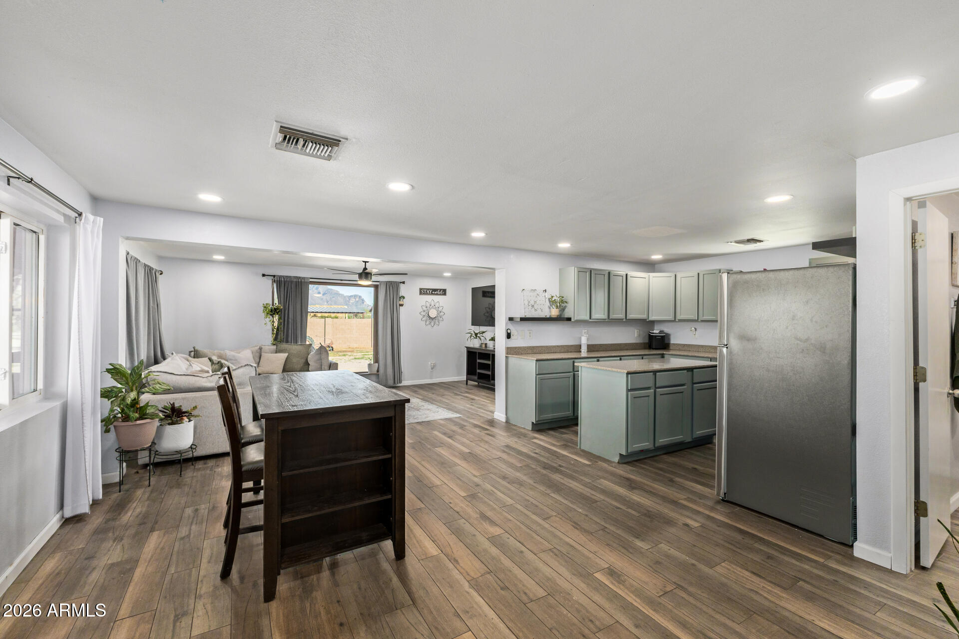 1925 East Greasewood Street Apache Junction, AZ 85119 - Photo 14 of 42 a kitchen with stainless steel appliances kitchen island granite countertop a refrigerator a stove a dining table and chairs with wooden floor