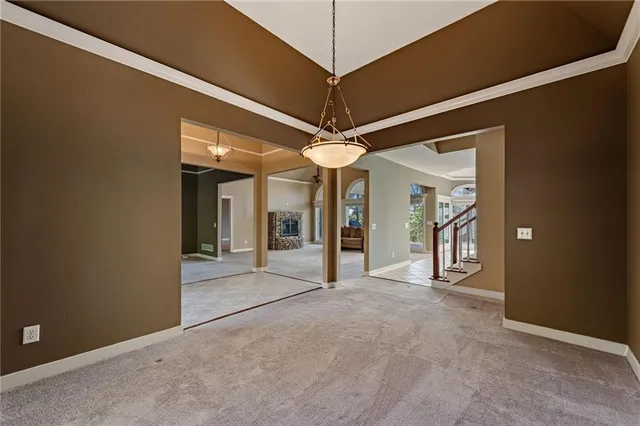 a view of an empty room with window and chandelier fan