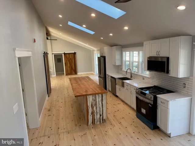 an empty room with wooden floor ceiling fan and windows