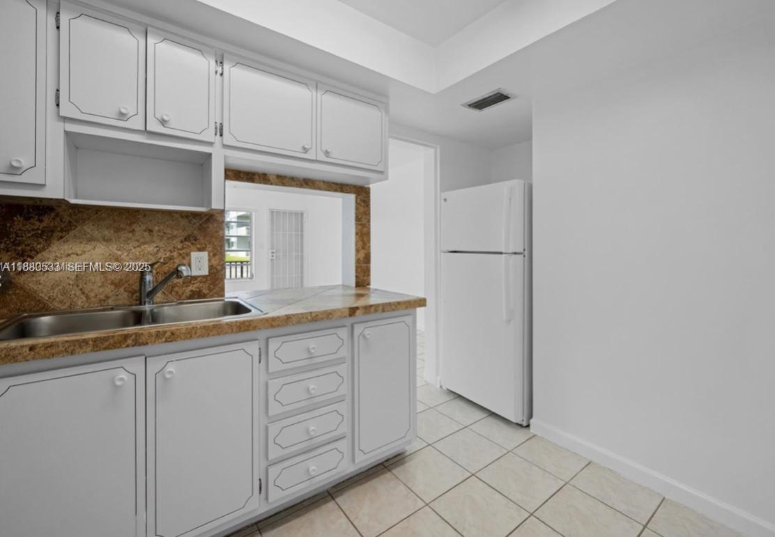 1400 Northeast 169th Street, Unit 115 Miami, FL 33162 - Photo 11 of 17 a kitchen with white cabinets and white appliances